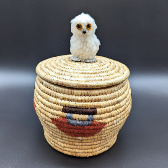 This Ookpik Lyme Grass Basket was created by Inuk artist Elisapi Weetaluktuk from the Inukjuak community and has the image of an ulu embroidered on it as well as a white ookpik on the basket cover