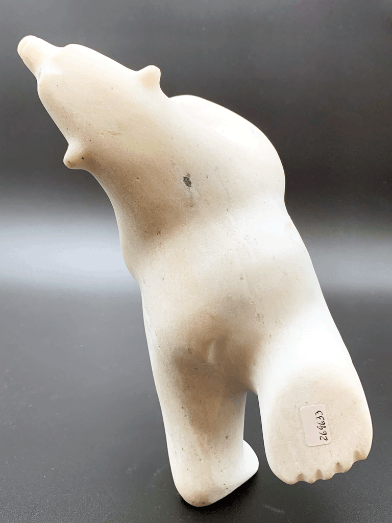 A dancing bear carved from white alabaster. This bear dances on one hind foot, with the other thrown back and arms spread wide. It throws its head back in jubilation. This bear faces away.