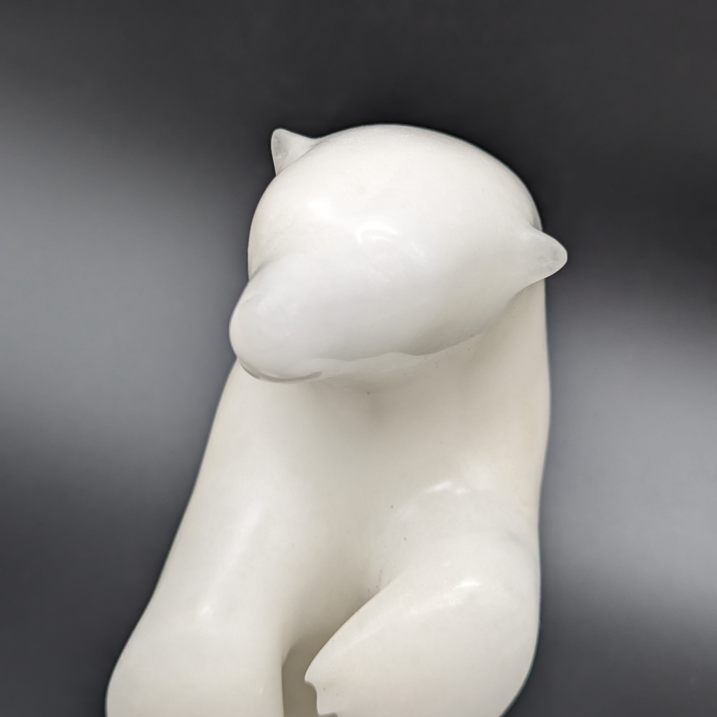A close up of the dancing bear carved from white alabaster. The bear dances on one foot, with the other hind foot raised and its paws in front of it. This bear faces the viewer directly.