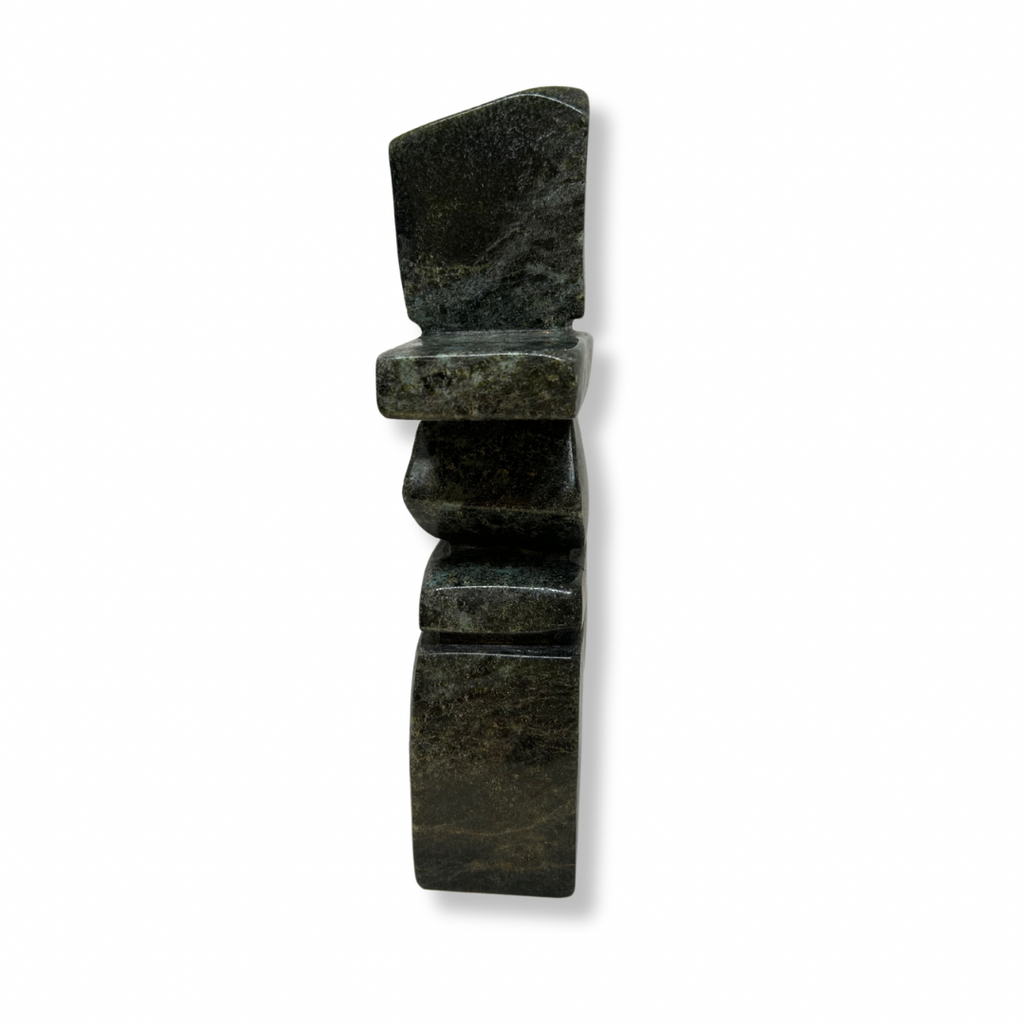 A graceful curving inukshuk carved from very dark green soapstone.