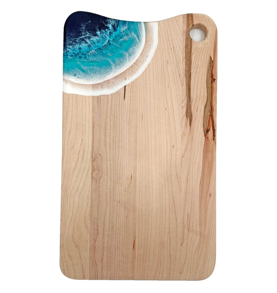 An x-large serving board made out of maple wood. In the corner are blue acrylic ocean waves.