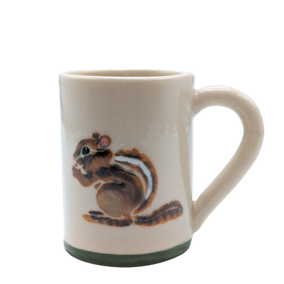 A handformed stoneware mug of white clay with ergonomic handle. The base is green and a chipmunk is handpainted with a mixture of traditional brush and sgraffito on the side.
