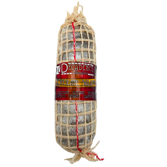 The dark chocolate cylinder of 'salami' is wrapped in a white net package, with a red and yellow label listing its ingredients.