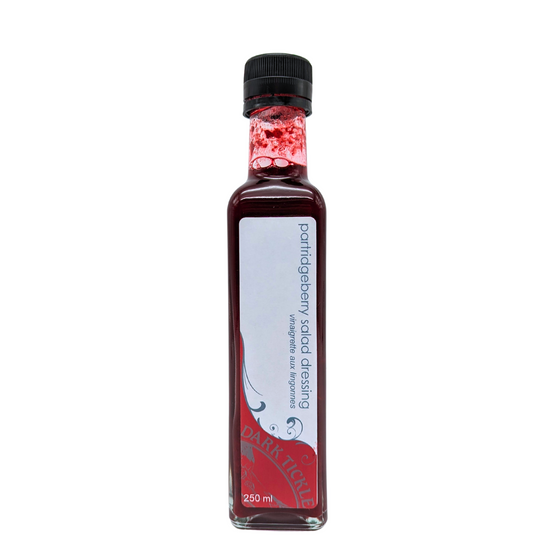 Tall Glass Bottle of Partridgeberry Salad Dressing from Dark Tickle. Dressing is Red in color.