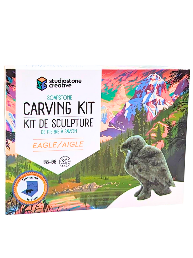 The box shows the green stone eagle of the carving kit against a beauftil and colourful backdrop of a mountain and forest scene, overlooking a tranquil lake.