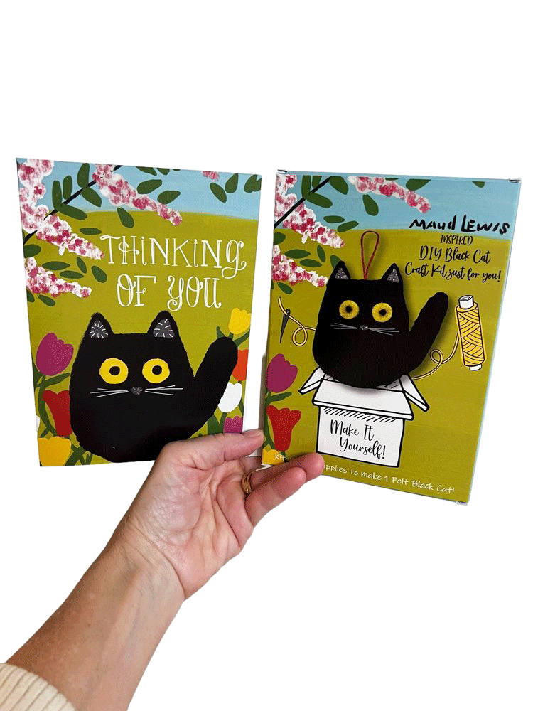 A bright and cheerful greeting card featuring one of Canadian icon Maud Lewis' signature black cats in a garden. The card reads "Thinking of You." Beside the card is a handcrafted ornament of the same black cat, in a DIY activity to sew your own Maud Lewis cat.