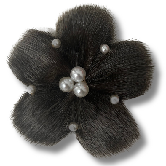 sealskin in the shape of a dark grey flower, with several pearl like circles in the center and in between each petal.