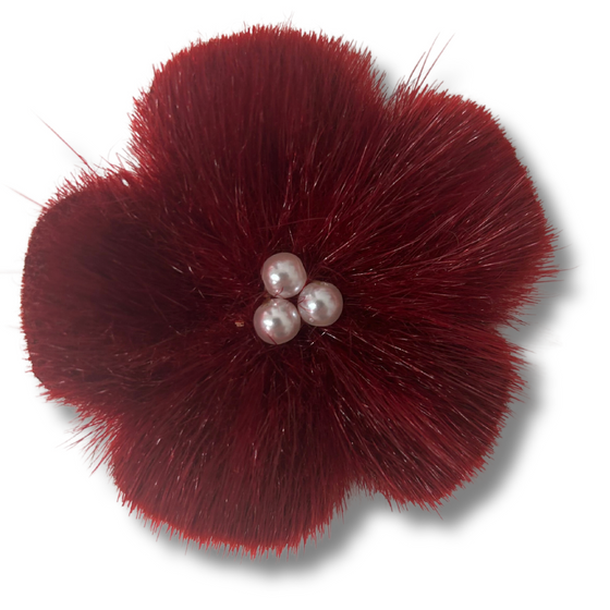 sealskin in the shape of a red flower, with three white pearl like circles in the center.