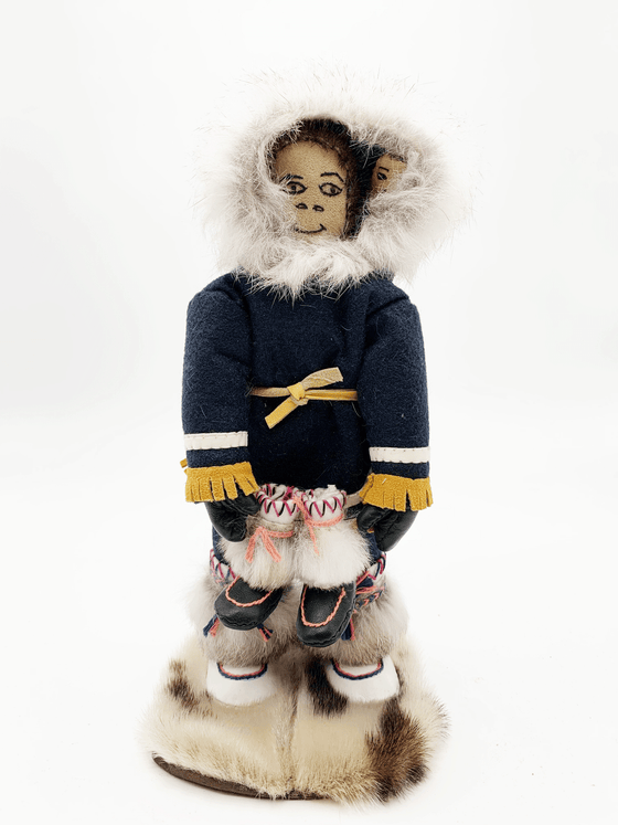 This handcrafted Inuit doll was created by Inuk artist Lizzie Sivuarapik in Puvurnituk, Nunavik and presents a person in blue traditional Inuit clothing holding a pair of shoes