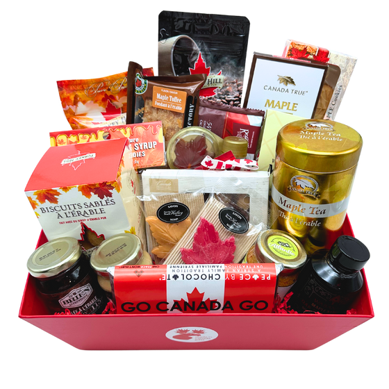 A red basket with a small circular Made in Gifts logo text and moose sticker in the center. Products inside are three spreads, a candle, soap, tea, coffee, two types of maple syrup, maple sugar, a lollipop, sea salt, maple shortbread, fudge, a chocolate bar, truffles, maple candies, toffee