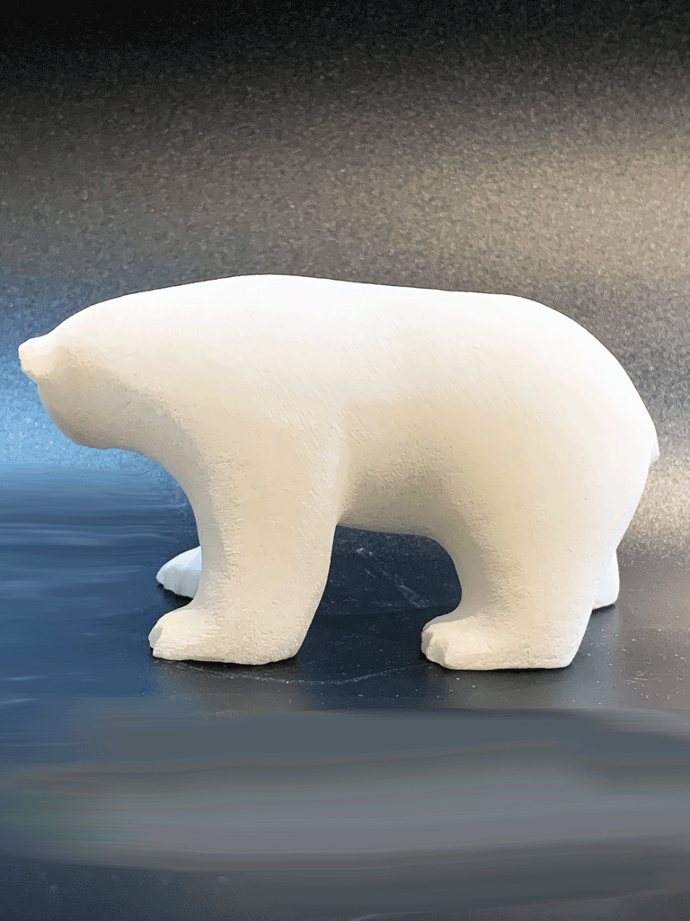 A polar bear carved from white alabaster stands on all fours. The bear's head is tilted, looking away. The artist has used a special technique to etch fur texture into the bear for added realism.