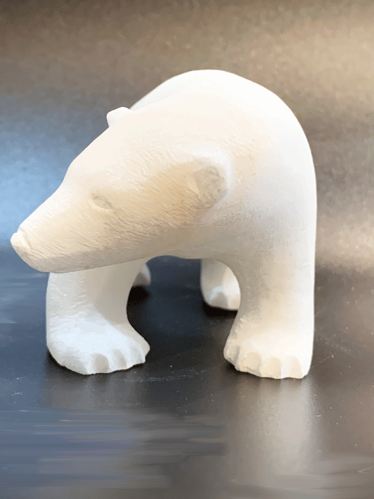 A polar bear carved from white alabaster stands on all fours. The bear's head is tilted, looking cheekily to the left. The artist has used a special technique to etch fur texture into the bear for added realism.
