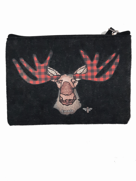 A charcoal felt pouch that features an art print of a moose. The moose has red buffalo check. The moose’s ear, nose, face and neck are all coloured with different shades of brown. Underneath the moose the word Canada has been written in white text. At the bottom right of the moose is the artists mark—a small picture of a bee. The zipper is black with a dark grey zipper puller with a rectangular piece of charcoal felt attached. 
