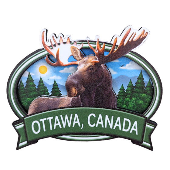 Green bordered oval shaped wooden magnet. Vibrant Canadian moose centered in a morning covered forest. The antlers embedded in the boarder above the edge. "Ottawa, Canada" in white written underneath. on a green ribbon banner.