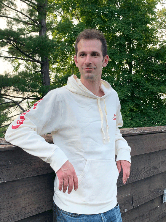 A white hoodie with Canada and a Canadian flag written on the left chest. Canada is written in red down the right sleeve.