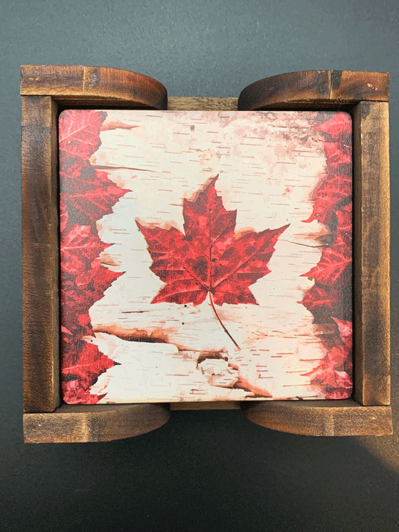 Set of four red Canadian maple leaf coasters with a large red maple leaf in the center and smaller maple leaves surrounding it and a wooden holder