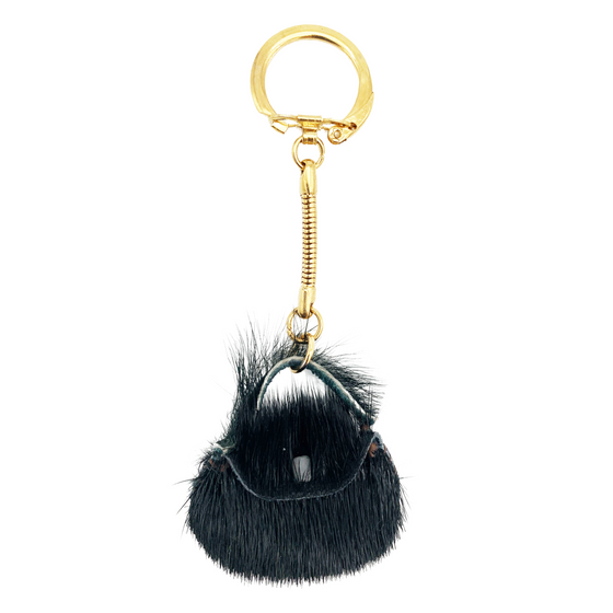 A navy sealskin purse keychain. The keychain hardware is gold.