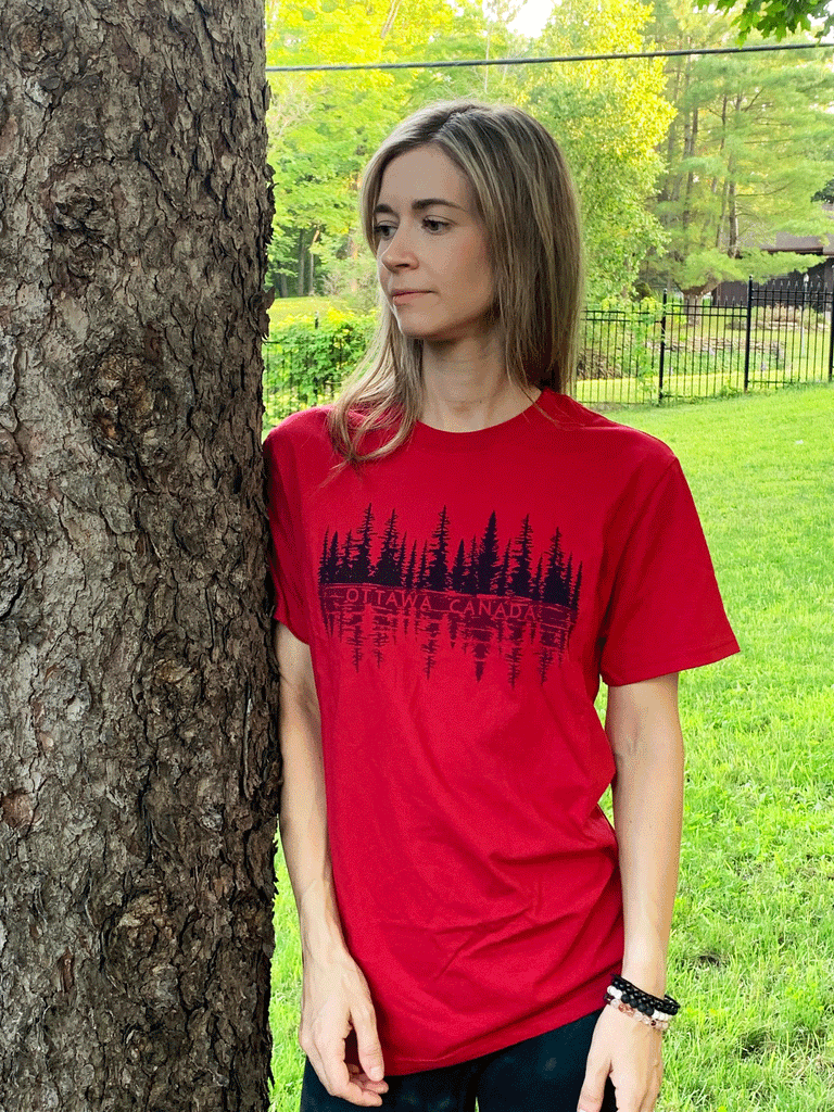 A red shirt. In the middle are black trees, with a lighter black water-like reflection. In the water is written "Ottawa Canada" in the same red as the shirt.