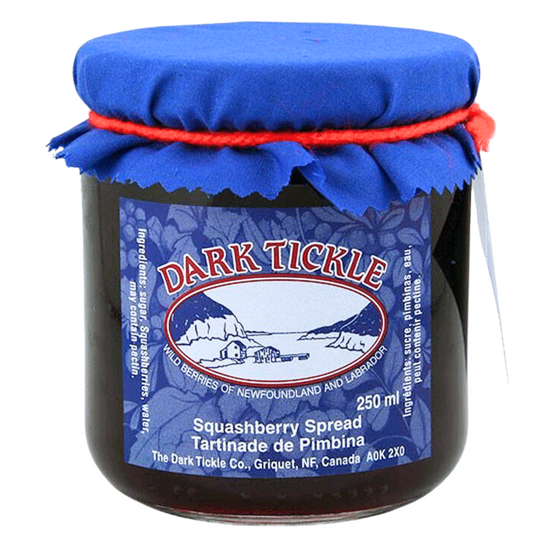 Glass Jar of Squashberry Jam from Dark Tickle in Newfoundland. Jam is dark blue/purple in color, and shut sealed with a tin lid.