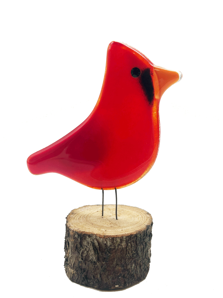 2-D glass red Cardinal. Has 2 small metal rods coming from the bottom of it that look like legs. The metal rods are attached to a piece of a tree that looks like a small tree stump. The background is white.