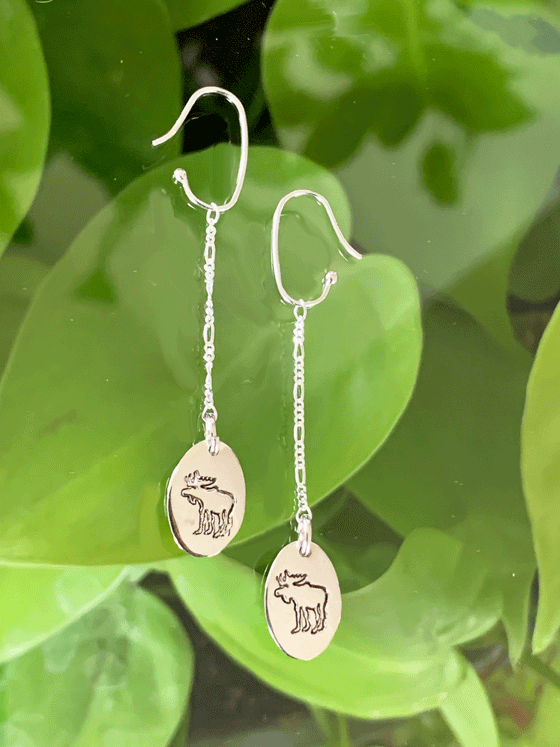 Drop earrings made of bright polished silver attached to sterling silver hooks.  The earrings are sterling ovals with a moose etched in the centre.