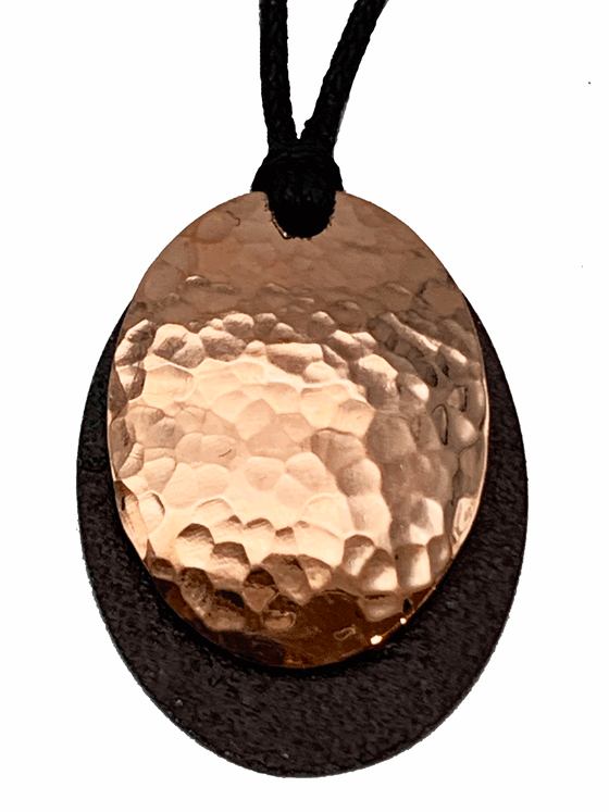 A beautiful necklace made of copper and tin mounted on a leather cord. The pendant is made of two layers: antique upcycled tin cut into an oval forms the base, and then a hammered copper circle is overlaid to create stunning contrast.
