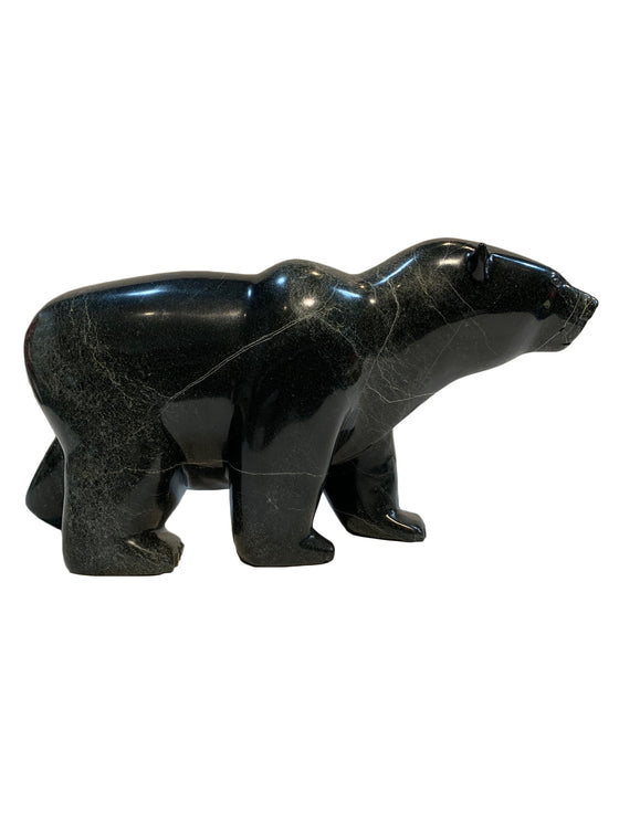 A large bear carved from dark green - almost black - stone. The bear walks on all fours, with its left hind leg slightly raised. The artist has carved powerful haunches and neck, conveying incredible power and strength in the animal. This bear faces right.