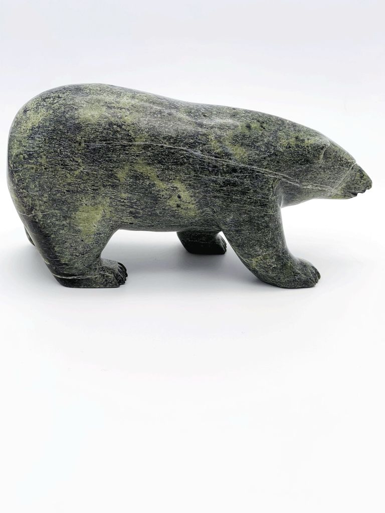 A bear carved of green soapstone stands on all fours. This bear faces right.