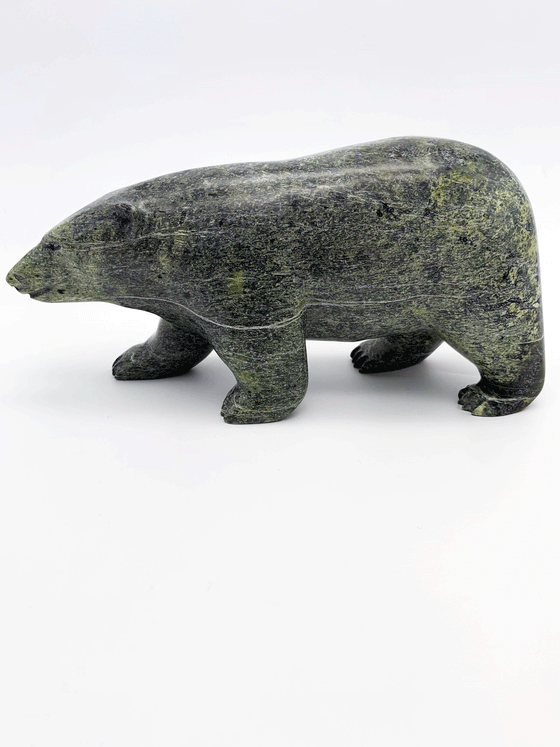 A bear carved of green soapstone stands on all fours. This bear faces left.