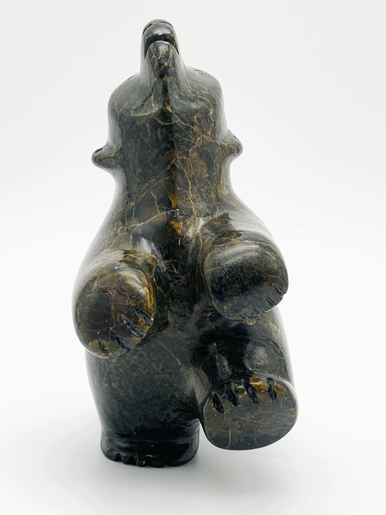 A dancing bear carved from greenish brown stone. This bear dances on one hind foot, with the other raised to one side and front paws raised. It throws its head back in jubilation. This bear faces the viewer.