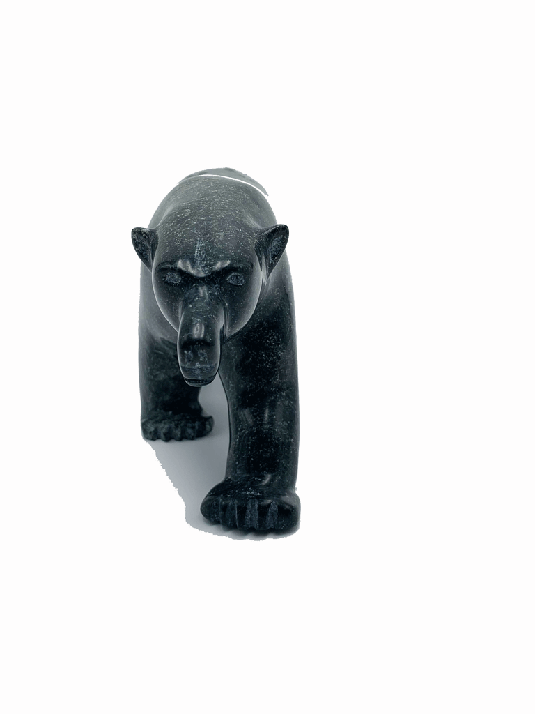 A powerful bear stands on all fours, carved from one piece of green soapstone. The bear faces the camera in this image, highlighting the detail in its sloping, inquisitive face.