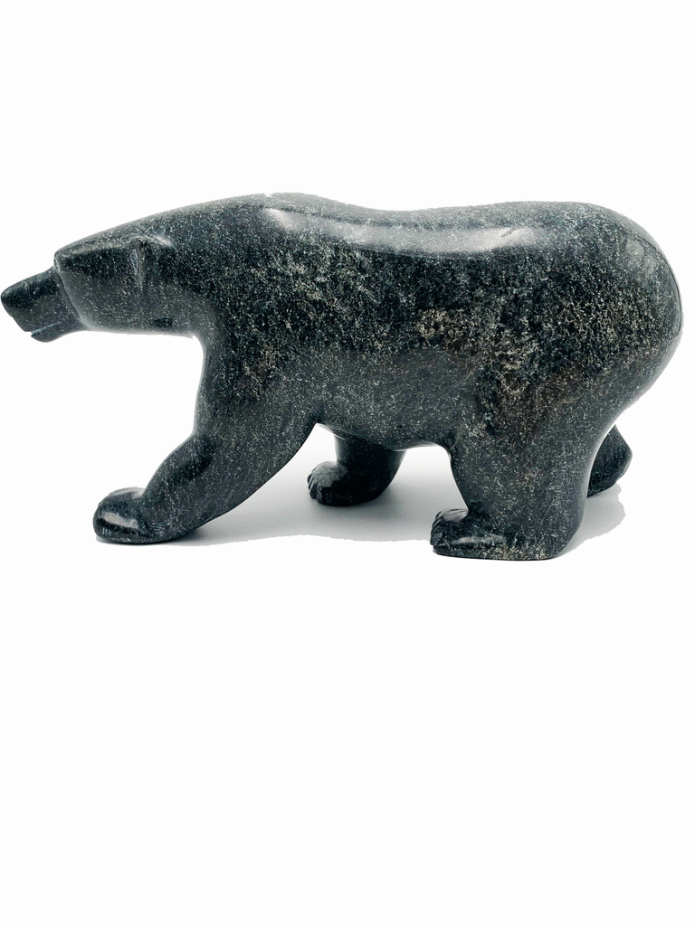 A powerful bear stands on all fours, carved from one piece of green soapstone. The bear faces left in this image.