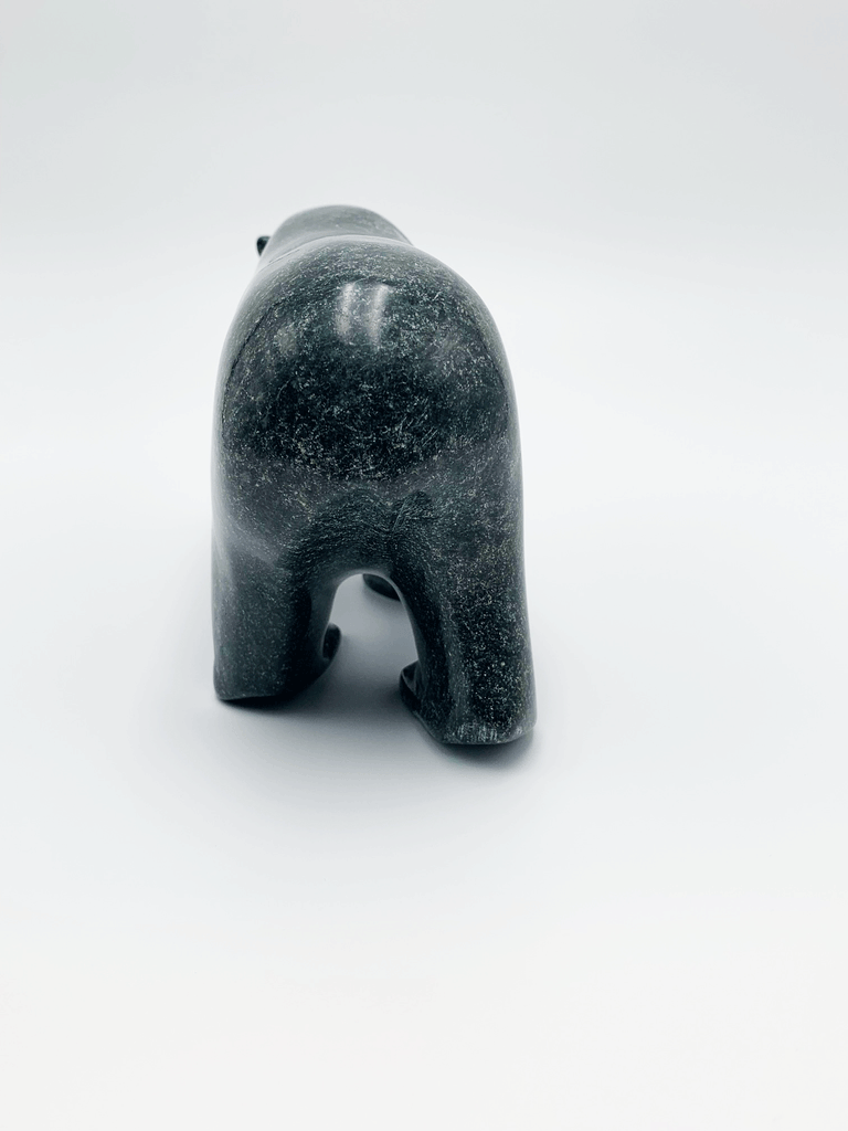 A powerful bear stands on all fours, carved from one piece of green soapstone. The bear faces away in this image.
