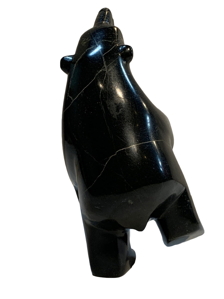 A dancing bear carved from jet black stone. This bear dances on one hind foot, with the other raised to one side and front paws raised. It throws its head back in jubilation. This bear faces away.