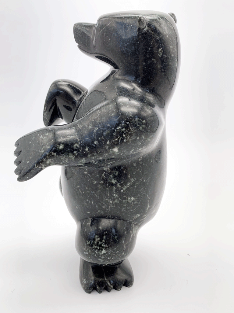 A dancing bear carved from jet black stone. This bear dances on one hind foot, with the other raised to one side and front paws raised. This bear faces left.
