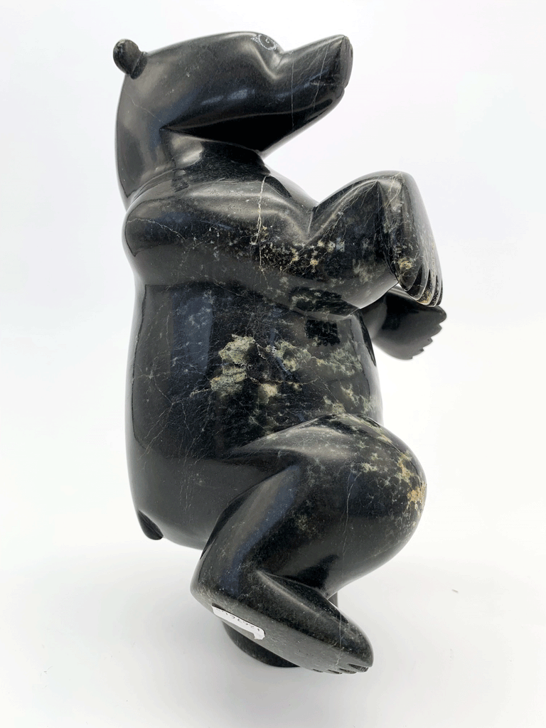 A dancing bear carved from jet black stone. This bear dances on one hind foot, with the other raised to one side and front paws raised. This bear faces right.