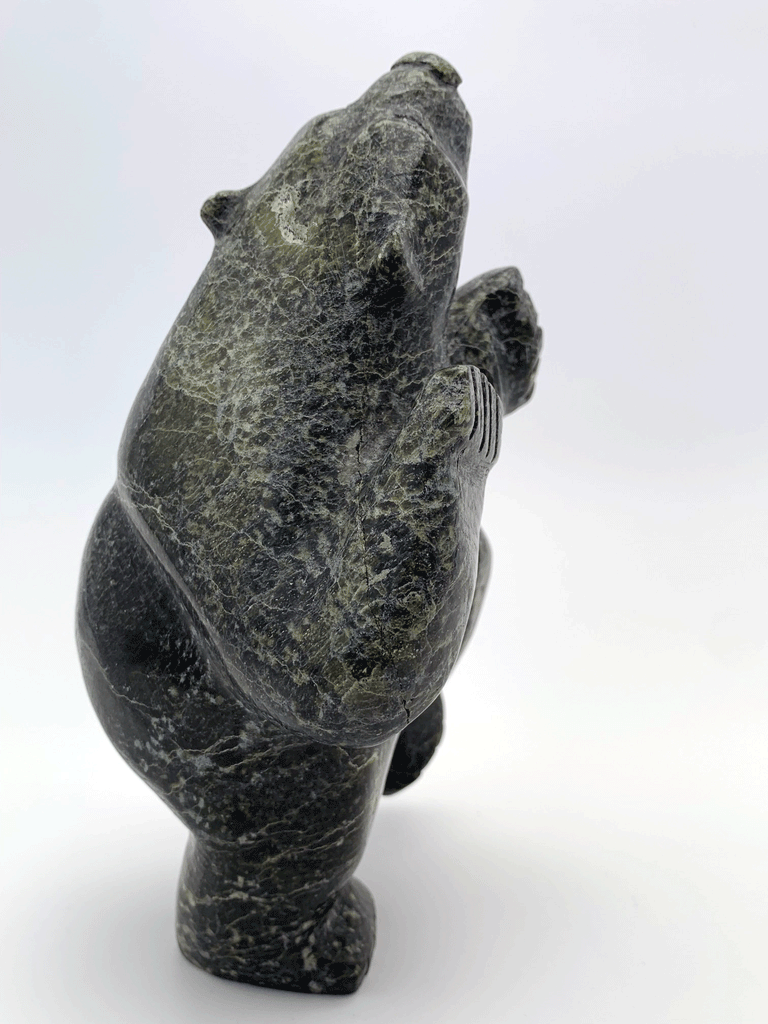 A dancing bear carved from jet black stone. This bear dances on one hind foot, with the other raised to one side and front paws raised. This bear faces away.