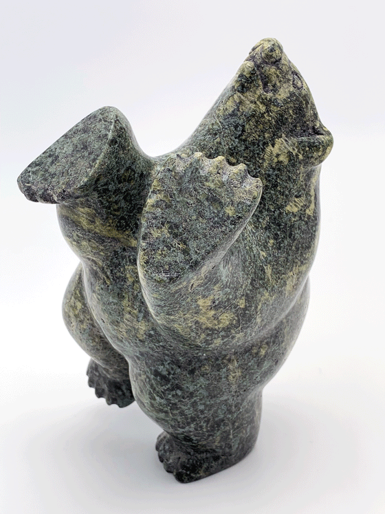 A dancing bear carved in mottled green stone. It stands on one hind leg with its face and front paws raised to the sky.