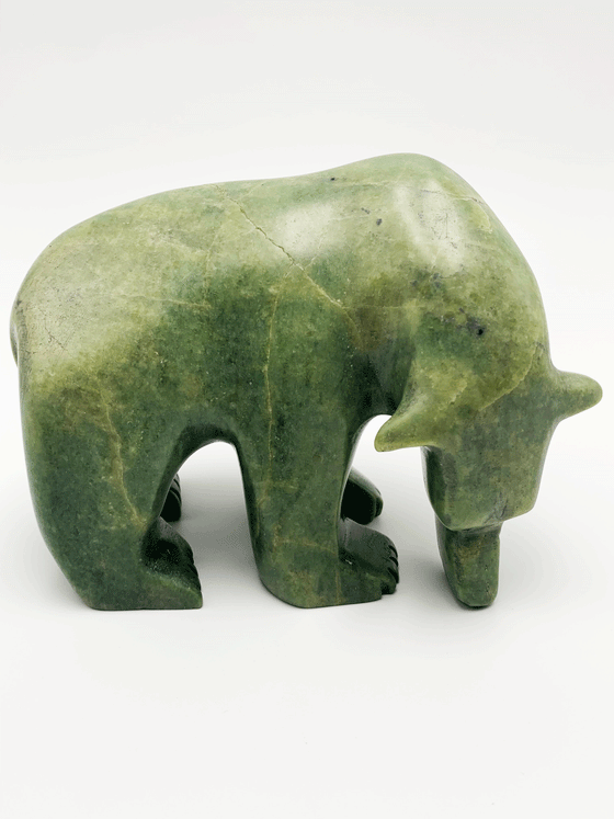 An inquisitive, bright green soapstone bear stands on all fours, head bowed as though examining something on the ground. This bear faces right.