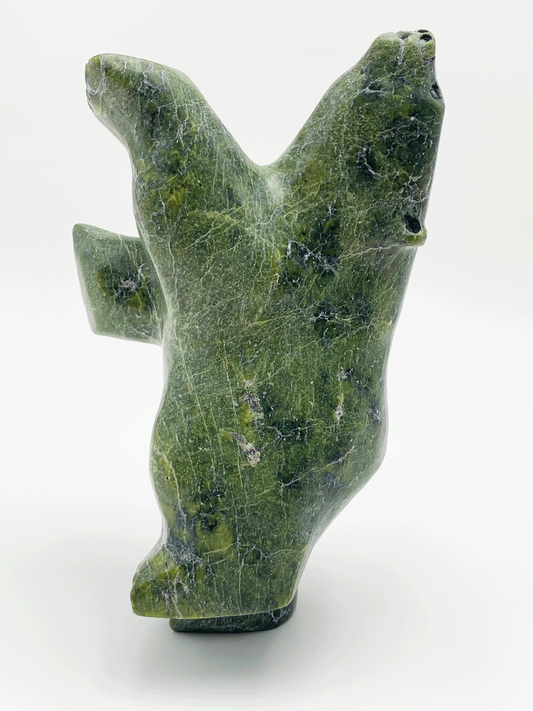 A dancing bear carved from brilliant green soapstone. The bear dances on one hind foot, with the other raised and its paws thrown up in front of it. The bear throws back its head in jubilation. This bear faces left.
