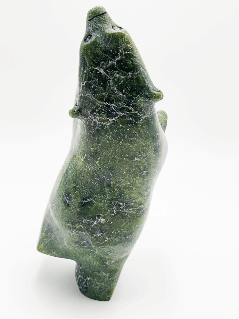 A dancing bear carved from brilliant green soapstone. The bear dances on one hind foot, with the other raised and its paws thrown up in front of it. The bear throws back its head in jubilation. This bear faces away.