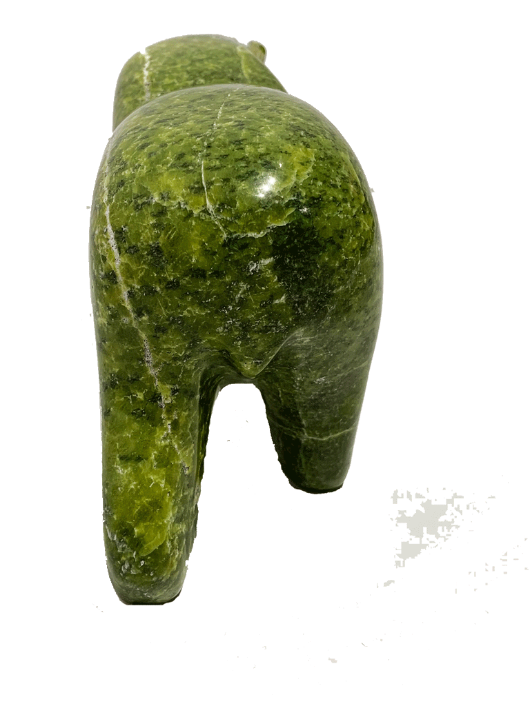 A long-necked bear carved from brilliant green soapstone walks on all fours. The head and forepaws are mottled with white, creating a beautiful contrast with the green. Its head is tilted to one side as though something has caught its attention. This bear faces away.
