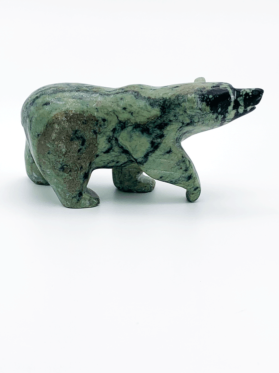 A walking bear carved from vividly contrasting green and black mottled stone. The natural mottling of the stone provides an additional layer of visual interest to the artist's smooth lines and delicate, expressive face. This bear faces right.