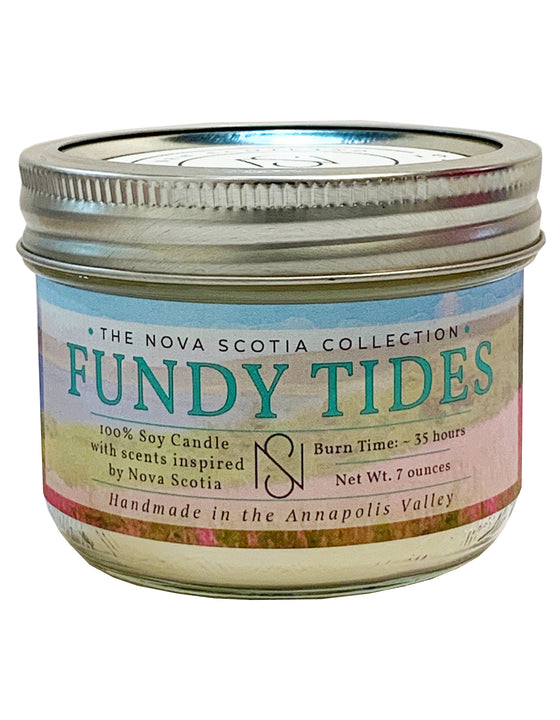 Cylindrical candle Jar with a tin cap. There is a label on the candle Jar, with a flower field background, and Fundy Tides written in the middle.