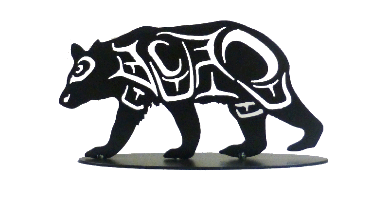 This metal sculpture shows the matte black silhouette of a hummingbird drawn in Coastal Salish style. The bear is mid stride, moving right to left. Coastal Salish shapes make the details of the bear’s broad legs and head.