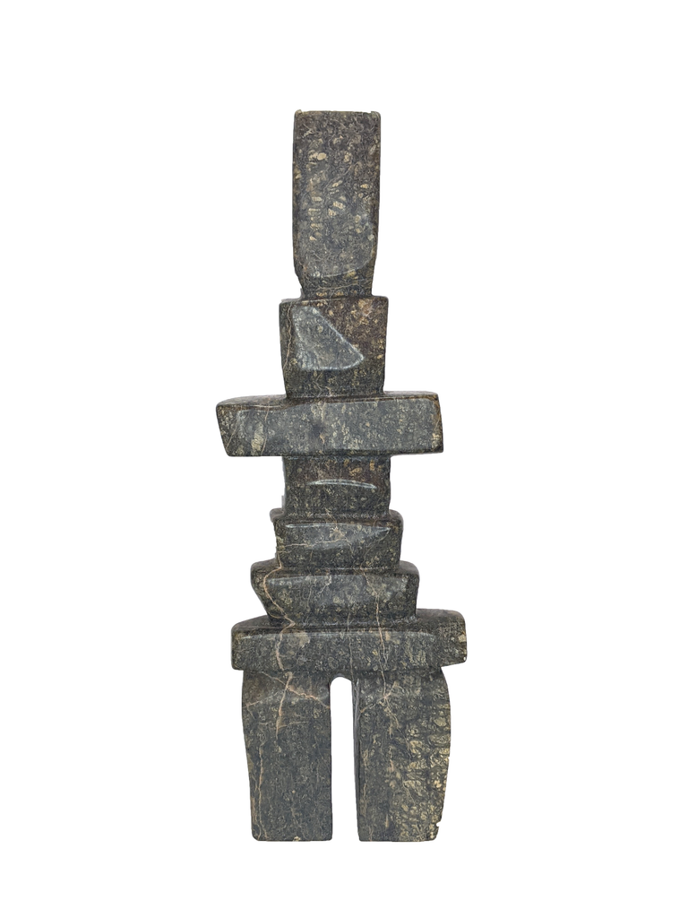 A tall, rigid inukshuk composed of stark, straight lines. Six slabs in varying lengths make up the body, with the legs and head being very tall by comparison. The stone is striking brown and green.