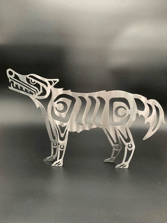 A Haida style wolf made of brushed steel. The wolf stands on four legs and looks up slightly.