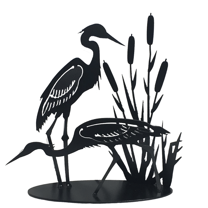 This metal sculpture shows the matte black silhouette of two herons standing with cattails. The left heron stands upright, while the right heron is leaning forward to look in the water. The wings of the herons have been partially punched out of the metal, and bent to render the birds in 3D. Individual wing feathers are visible. The cattails are cut very delicately and in lifelike shape and proportion to the herons. The piece sits on a long oval base.