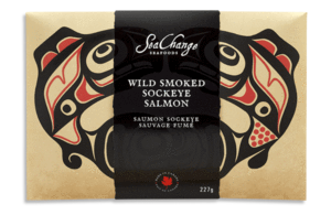 Picture features a single 227g smoked salmon travel pack. On the travel pack, Haida art of the Canadian pacific salmon by artist Don Yeomans is shown.