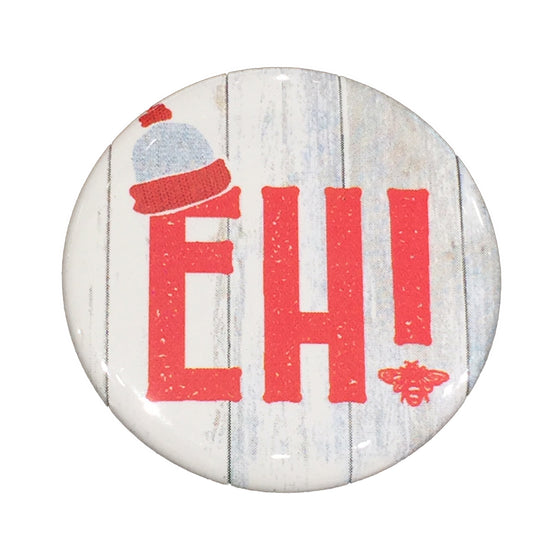 This magnet shows the word “Eh” in bold red text on a pale, wood-textured background. A small white and red toque rests on top of the E.